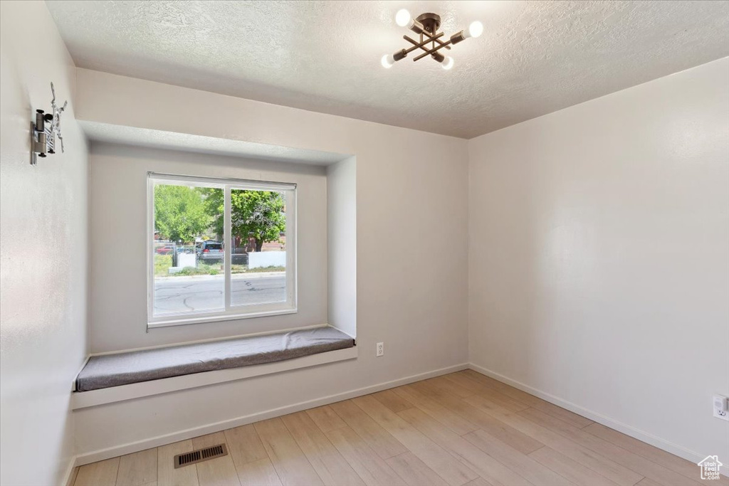 Empty room featuring visible vents, baseboards, a textured ceiling, and wood finished floors