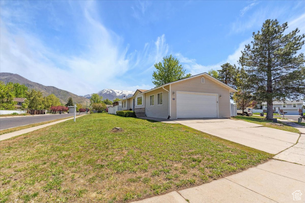 View of front facade with a front lawn, a mountain view, and concrete driveway