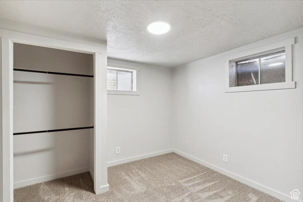 Basement with a textured ceiling, baseboards, and carpet