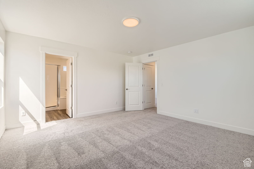 Unfurnished bedroom featuring carpet floors, baseboards, and ensuite bathroom