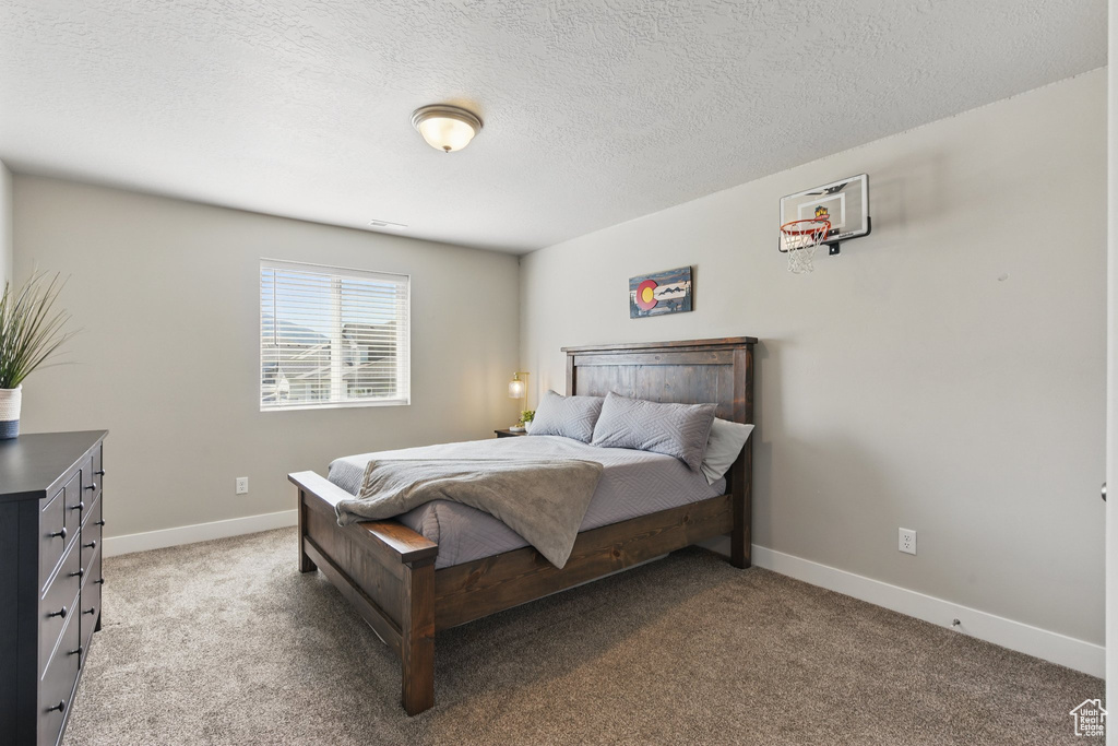 Bedroom featuring light colored carpet, a textured ceiling, and baseboards