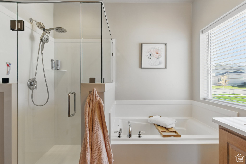 Bathroom featuring a shower stall, a garden tub, and vanity