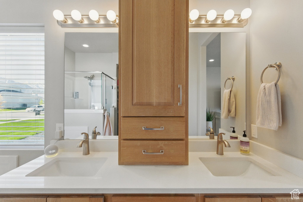 Bathroom with double vanity, a sink, and a stall shower