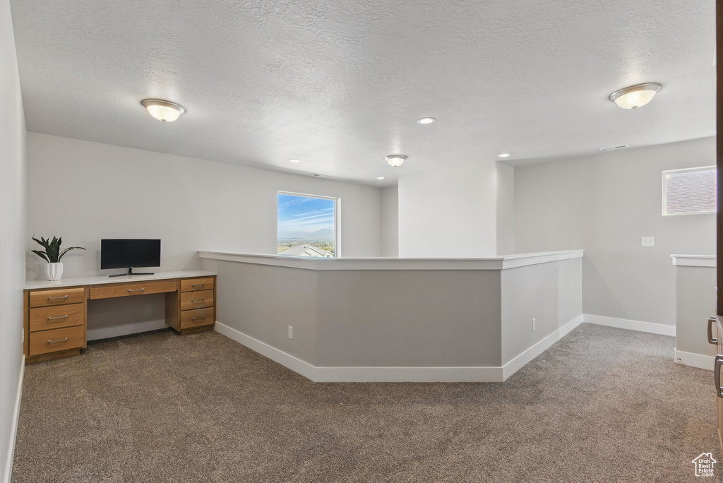 Unfurnished office with carpet floors, baseboards, and a textured ceiling