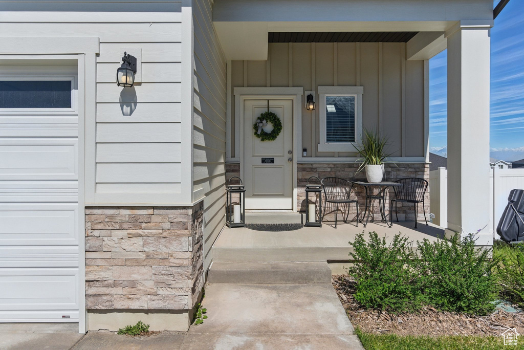 Entrance to property with board and batten siding, covered porch, and stone siding