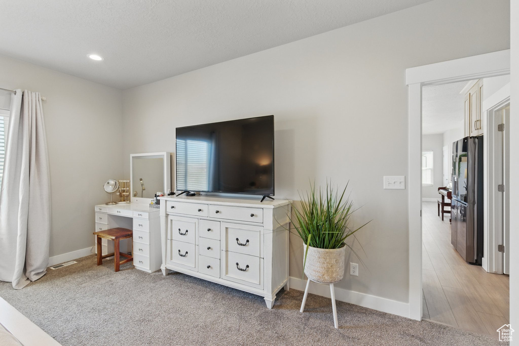 Bedroom featuring baseboards, freestanding refrigerator, visible vents, and multiple windows