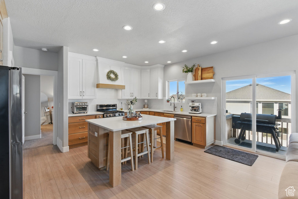 Kitchen featuring light wood-style floors, a breakfast bar area, light countertops, a sink, and stainless steel appliances