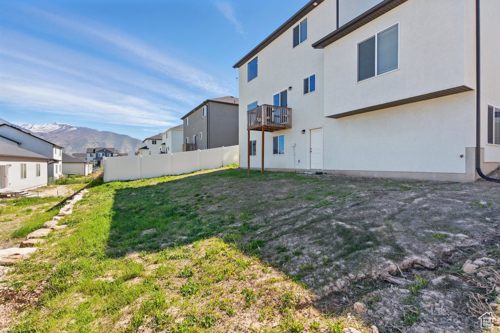 View of yard featuring a mountain view, a balcony, a residential view, and fence