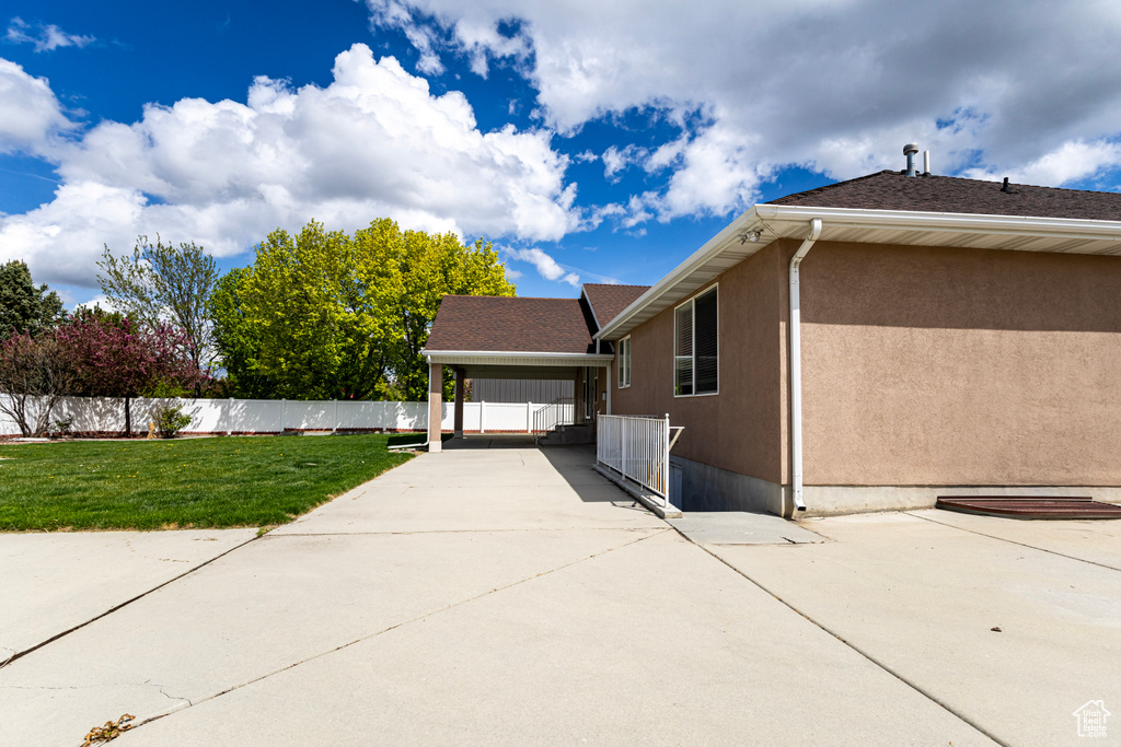 View of home's exterior with stucco siding, fence, and a yard