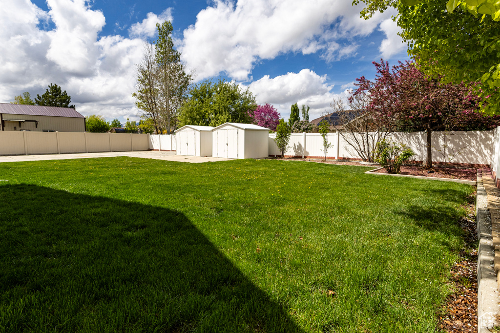 View of yard featuring an outdoor structure, a fenced backyard, and a storage unit