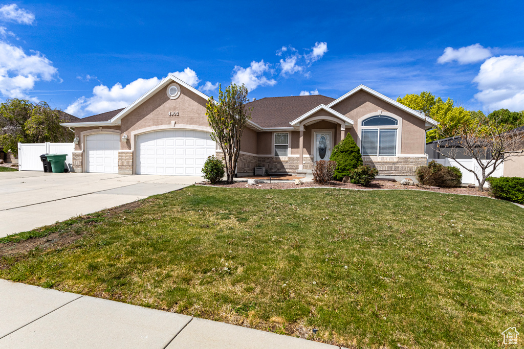 Ranch-style house with a garage, a front lawn, stone siding, stucco siding, and concrete driveway