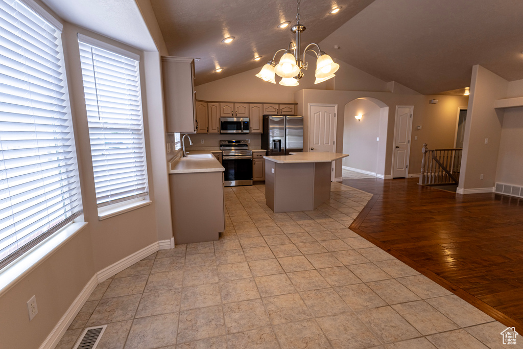 Kitchen with light countertops, arched walkways, a center island, stainless steel appliances, and visible vents