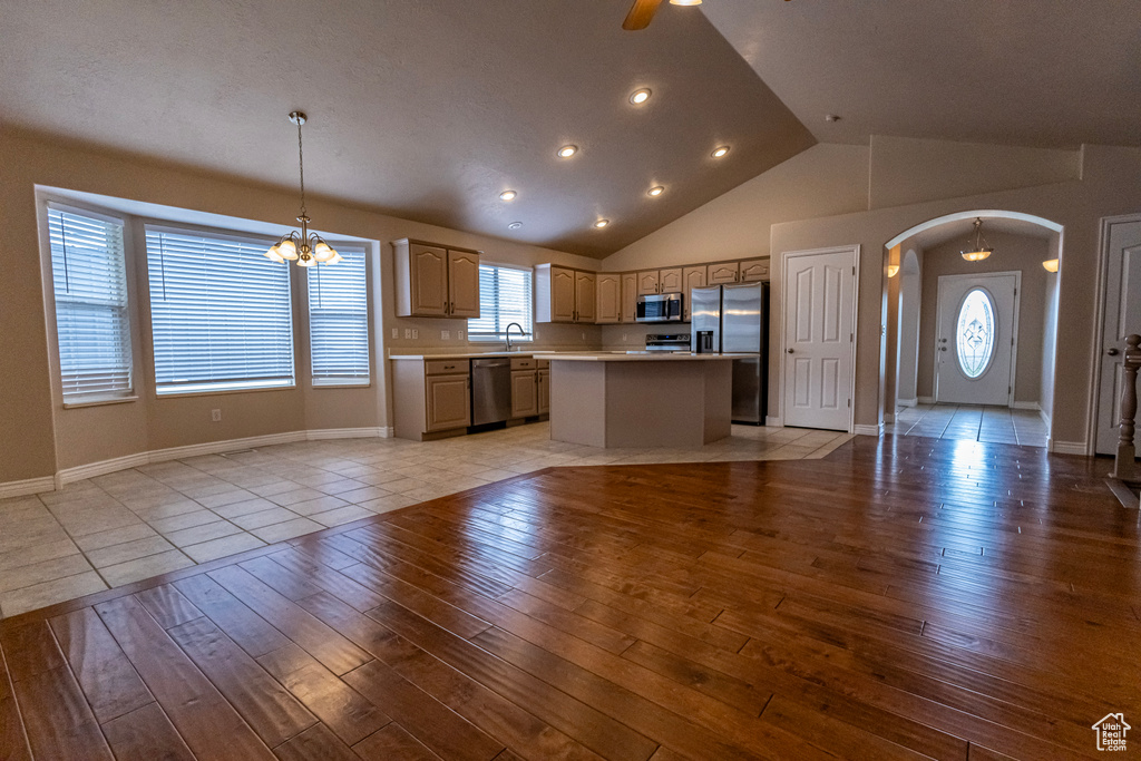 Kitchen featuring light wood finished floors, light countertops, arched walkways, a center island, and stainless steel appliances