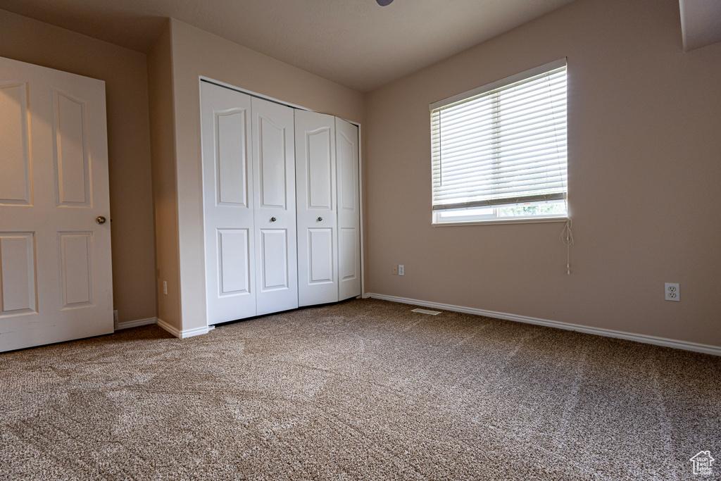 Unfurnished bedroom with baseboards, carpet, and a closet