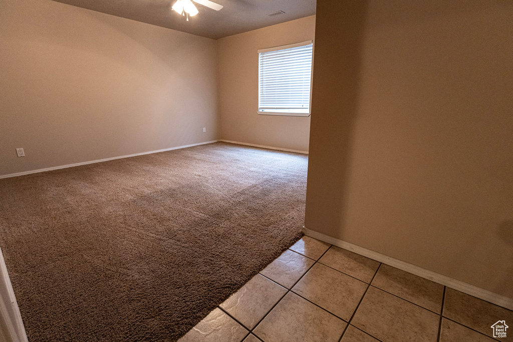 Spare room featuring baseboards, ceiling fan, visible vents, and light carpet