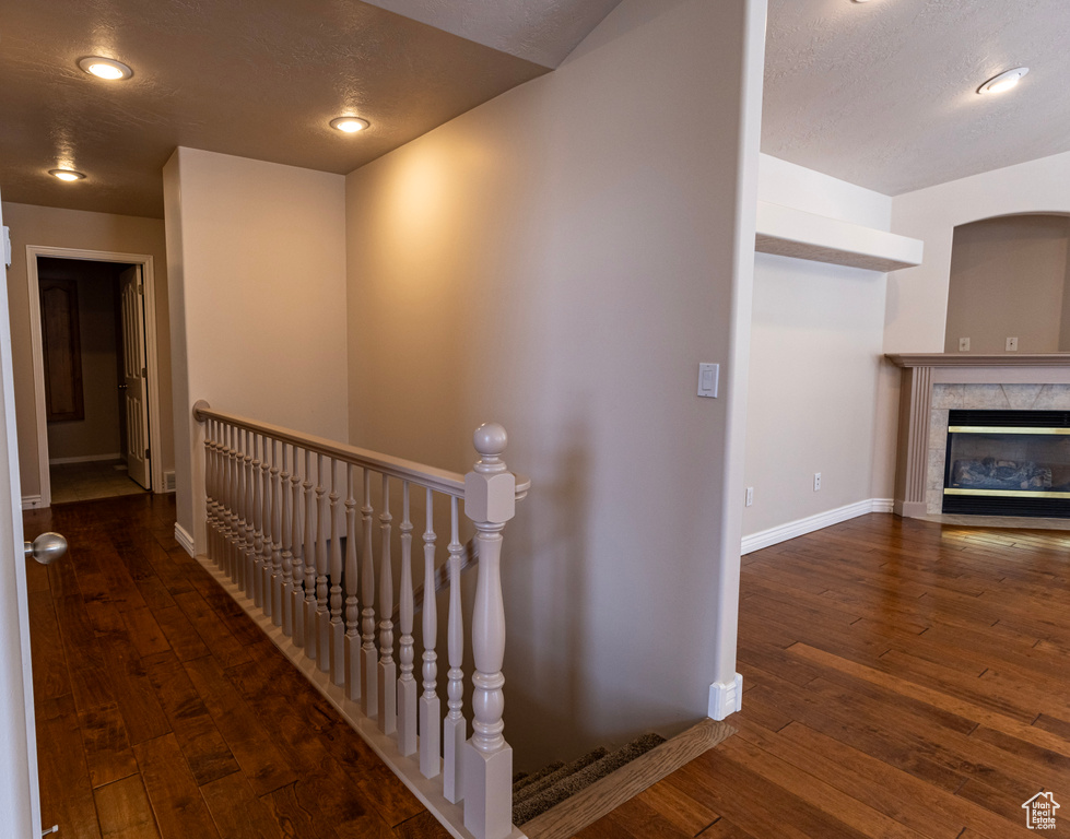Hallway with a textured ceiling, baseboards, an upstairs landing, and hardwood / wood-style floors