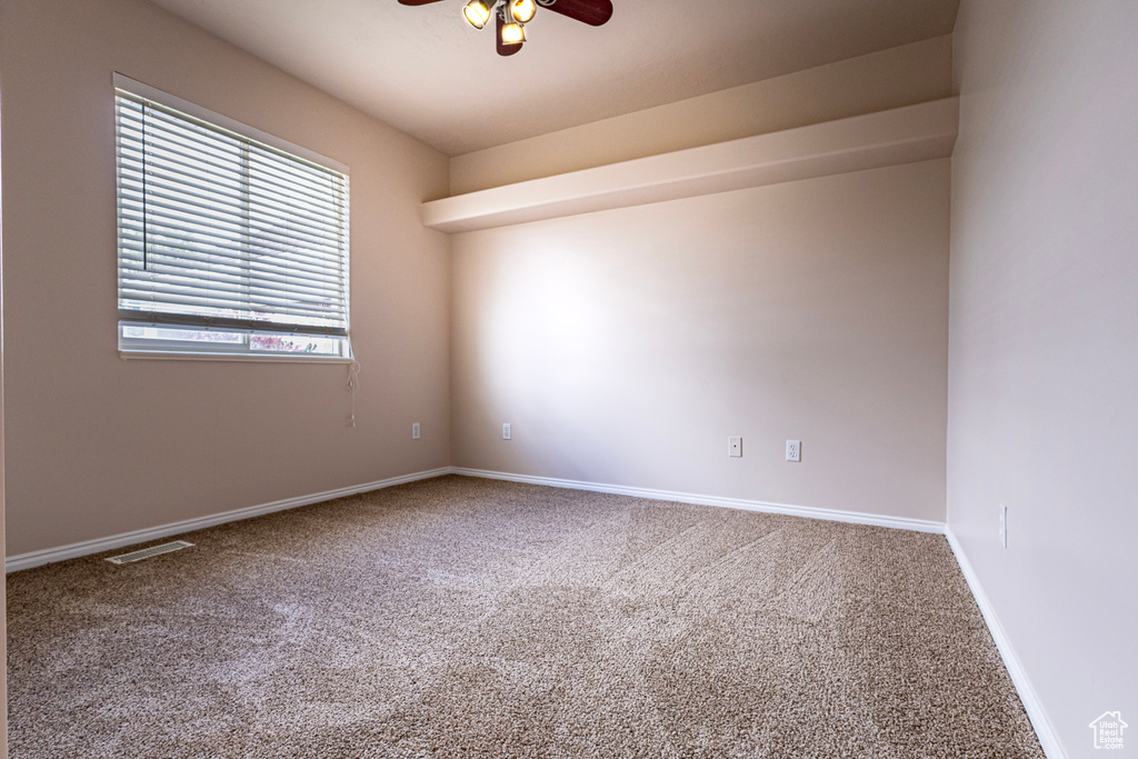 Carpeted empty room with baseboards and a ceiling fan