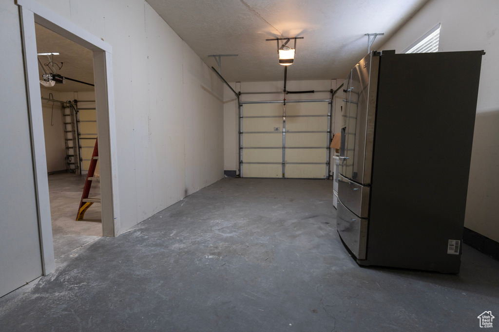 Garage with a garage door opener and freestanding refrigerator