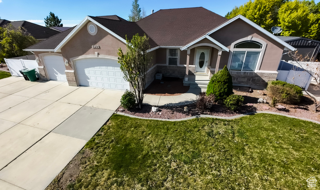 Single story home featuring fence, concrete driveway, an attached garage, stone siding, and stucco siding