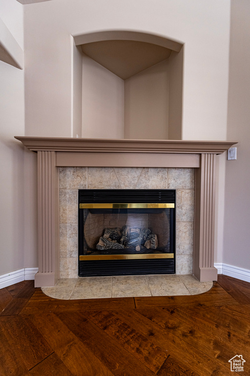 Room details with a tiled fireplace, baseboards, and wood finished floors