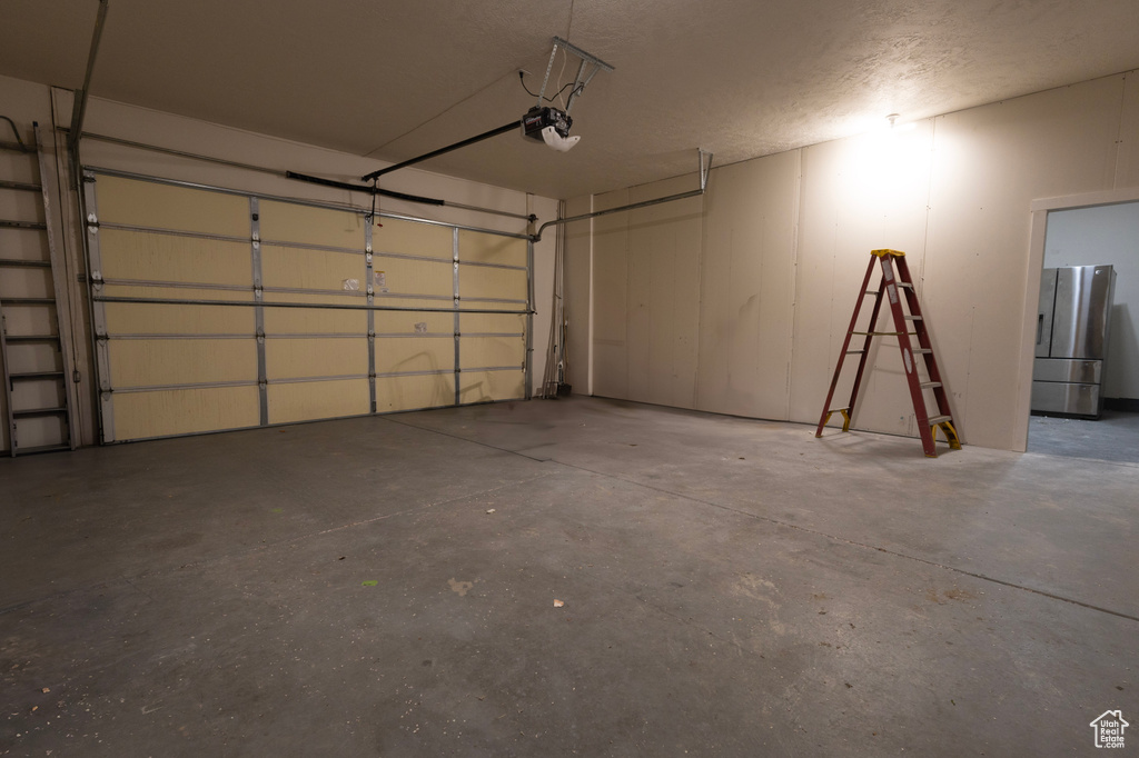 Garage with freestanding refrigerator and a garage door opener