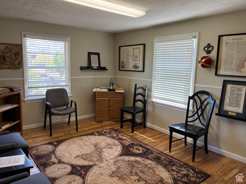Sitting room featuring a wainscoted wall, a textured ceiling, and wood finished floors