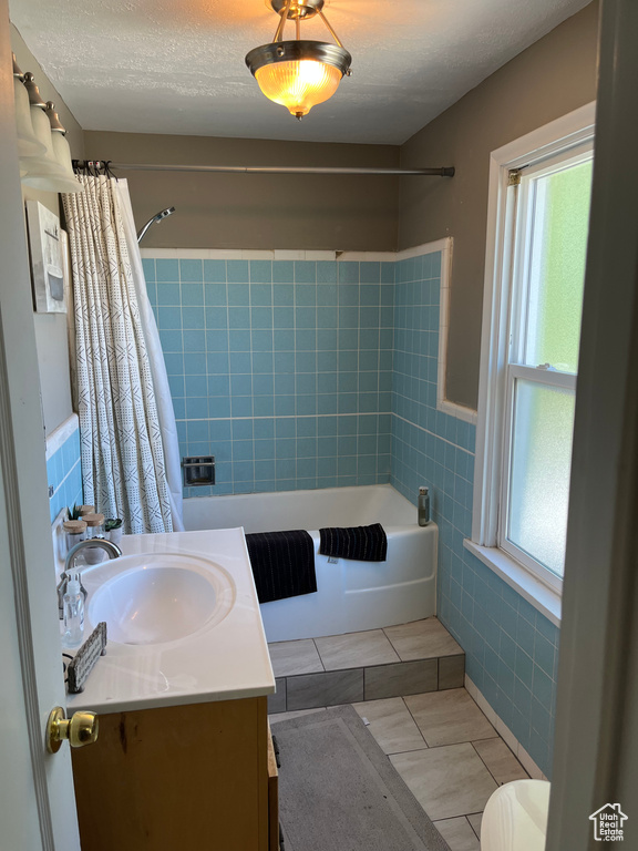 Bathroom with tile walls, tile patterned flooring, wainscoting, vanity, and shower / bath combo with shower curtain