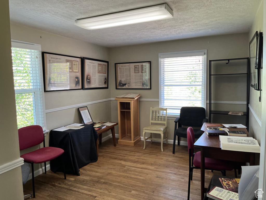 Office space featuring baseboards, plenty of natural light, a textured ceiling, and wood finished floors