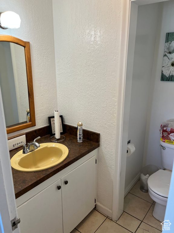 Bathroom with toilet, tile patterned floors, and vanity