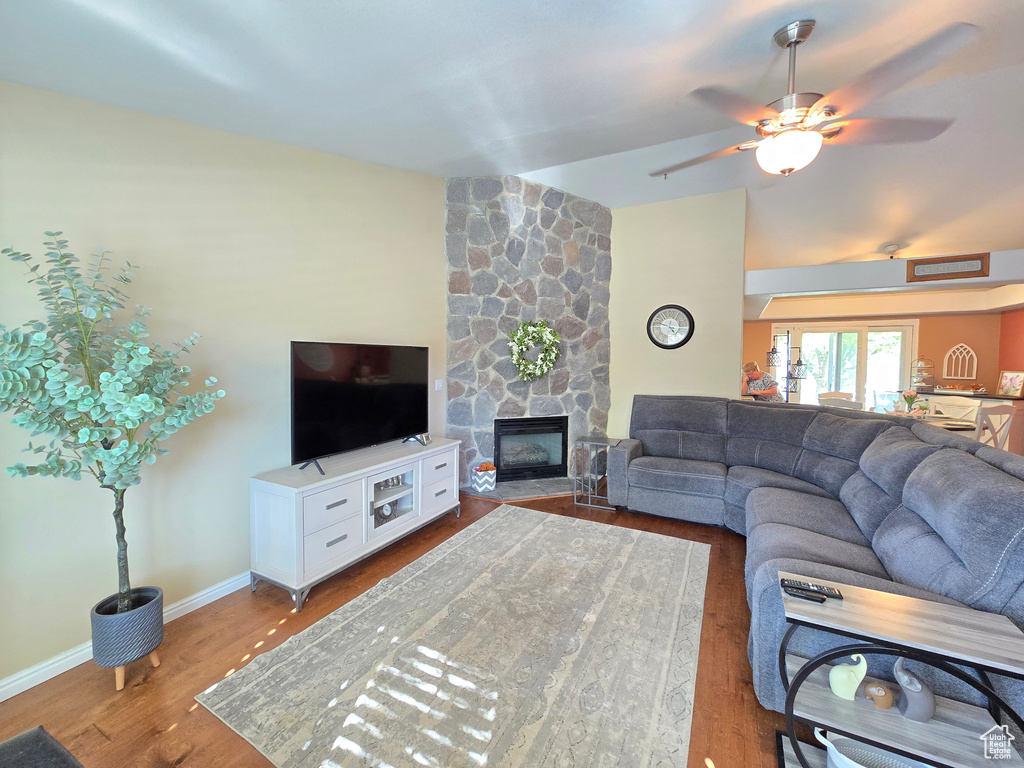 Living area with baseboards, a ceiling fan, wood finished floors, and a fireplace