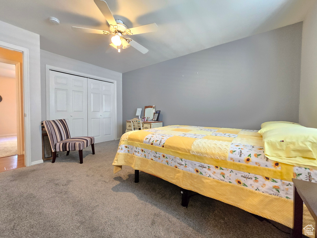 Carpeted bedroom featuring a ceiling fan and a closet