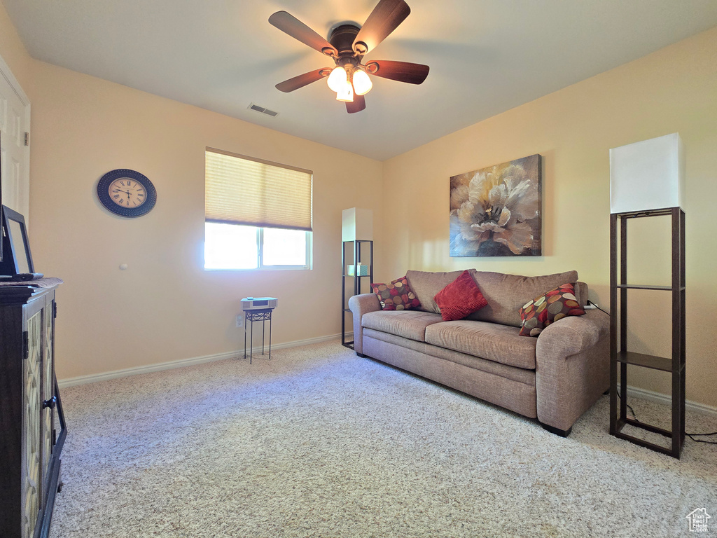 Carpeted living area featuring baseboards, ceiling fan, and visible vents