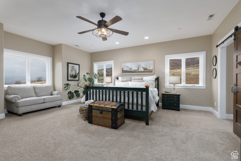 Carpeted bedroom with a barn door and ceiling fan