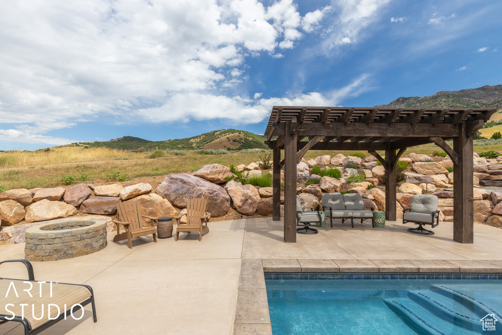 View of swimming pool with a mountain view, a pergola, a patio area, and an outdoor fire pit