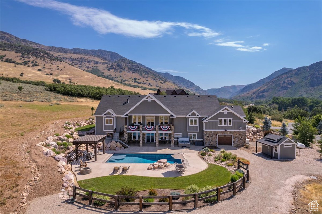 Rear view of property with a yard, a shed, a fenced in pool, a mountain view, and a patio area