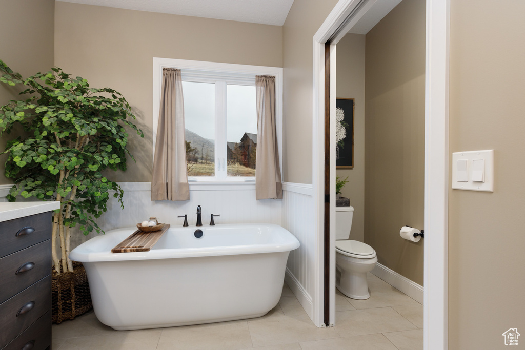 Bathroom with tile patterned flooring, a bath, and toilet