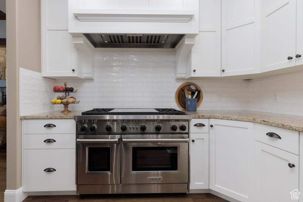 Kitchen featuring white cabinetry, custom exhaust hood, and range with two ovens