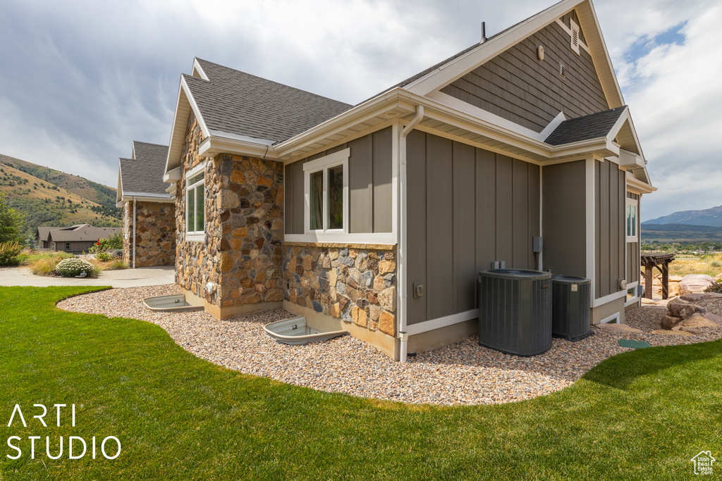 View of home\\\\\\\'s exterior featuring cooling unit, a mountain view, and a lawn