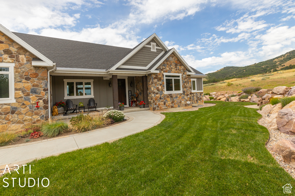 Craftsman house with a mountain view, a front yard, and covered porch