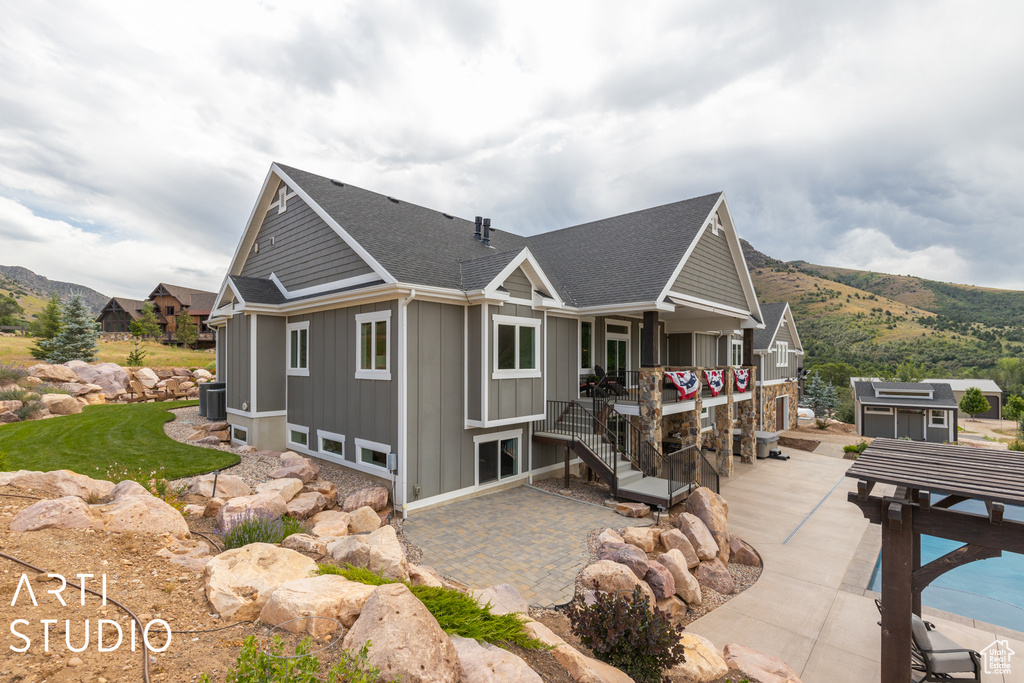 Rear view of property with a mountain view, a patio area, and central air condition unit