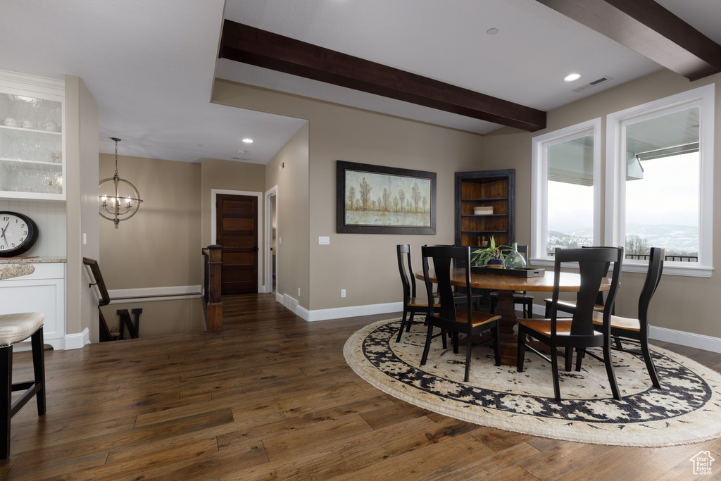 Dining area featuring beamed ceiling, dark hardwood / wood-style flooring, and an inviting chandelier