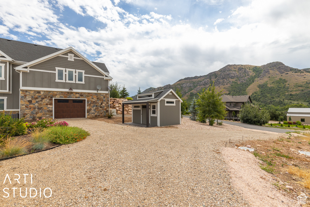 View of side of property with a mountain view and a garage
