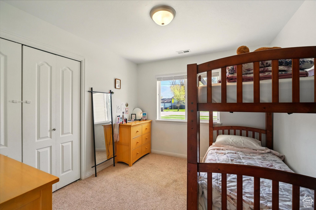 Bedroom with visible vents, a closet, and light colored carpet