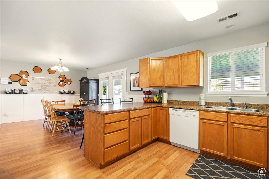 Kitchen featuring visible vents, light wood-type flooring, dishwasher, a sink, and a peninsula