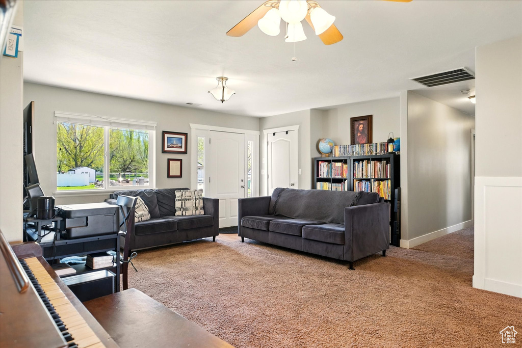 Carpeted living room with baseboards, a ceiling fan, and visible vents