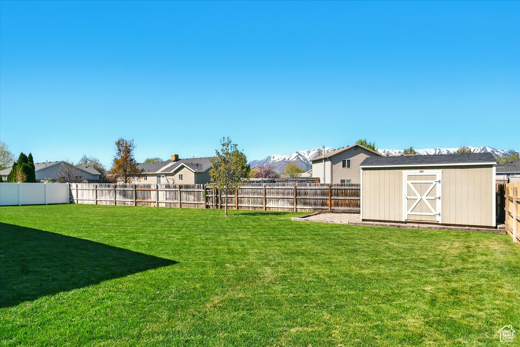 View of yard featuring a fenced backyard, an outbuilding, a shed, and a residential view