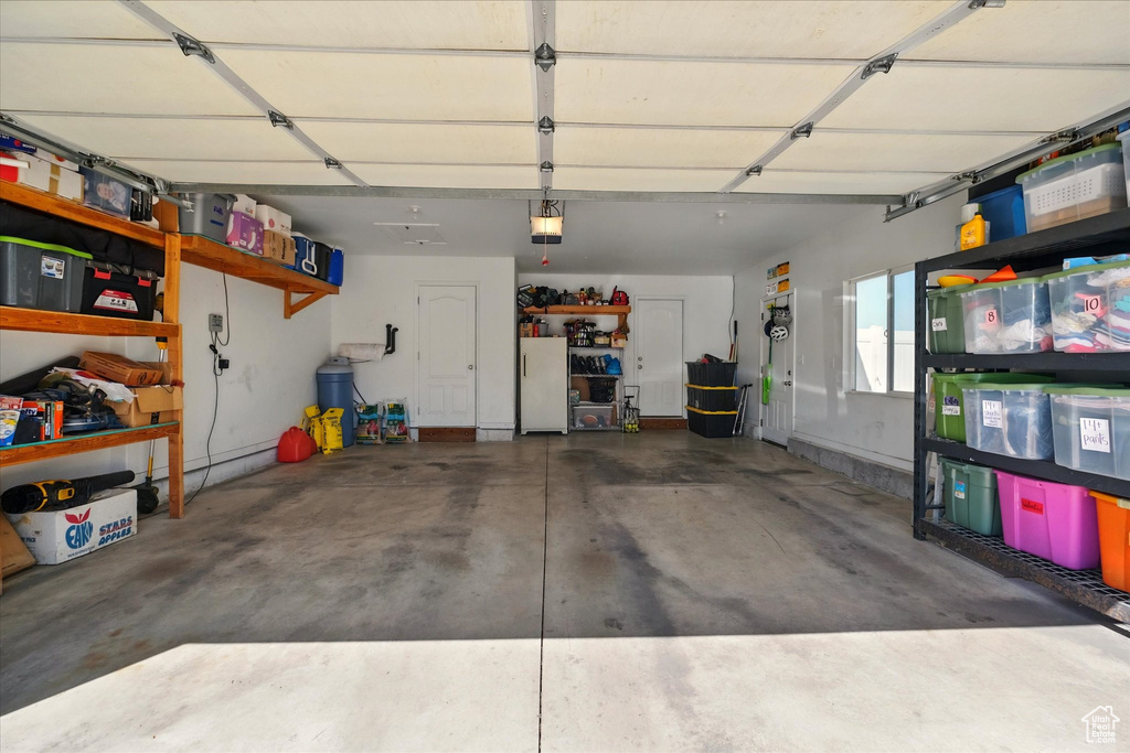 Garage with freestanding refrigerator and a garage door opener