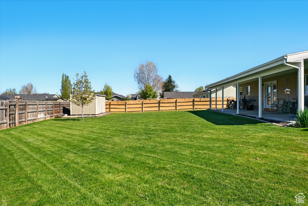 View of yard with a storage shed, an outbuilding, a fenced backyard, and a patio area
