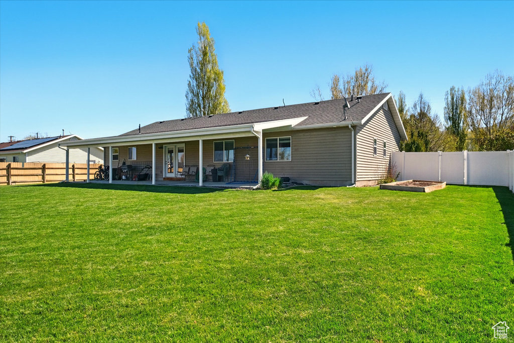 Rear view of property featuring a yard, a patio, a fenced backyard, and a vegetable garden