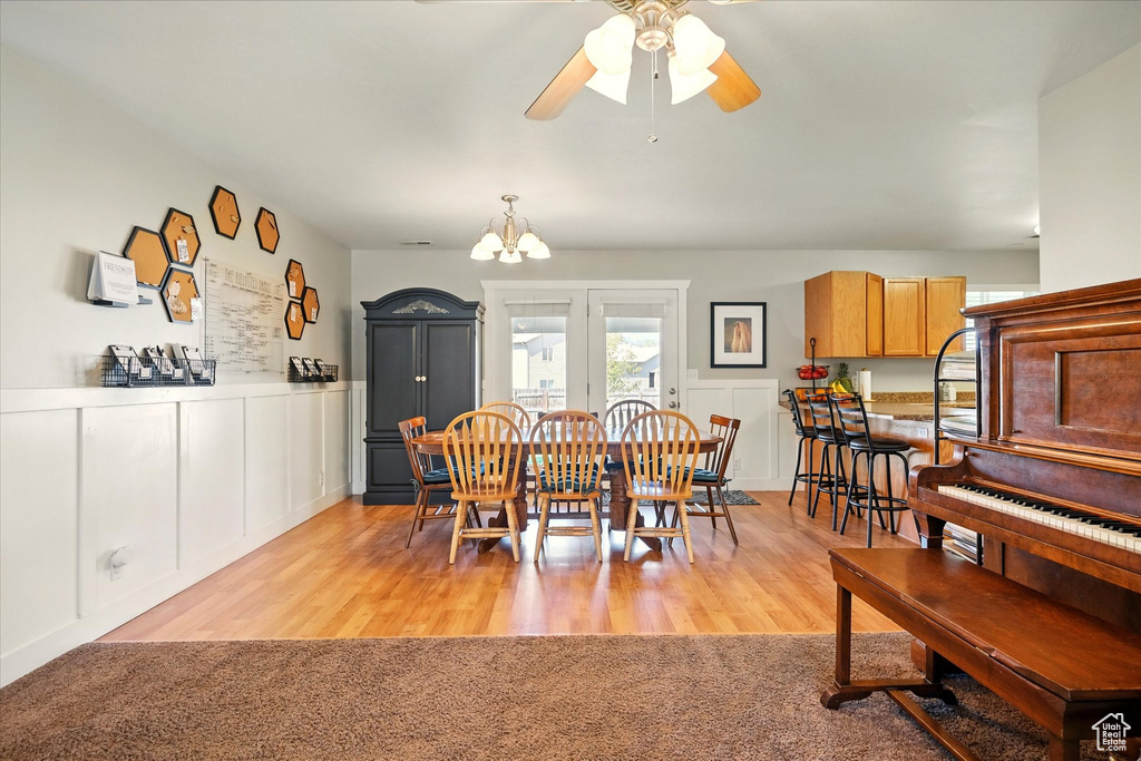 Dining area with light wood-type flooring and ceiling fan with notable chandelier